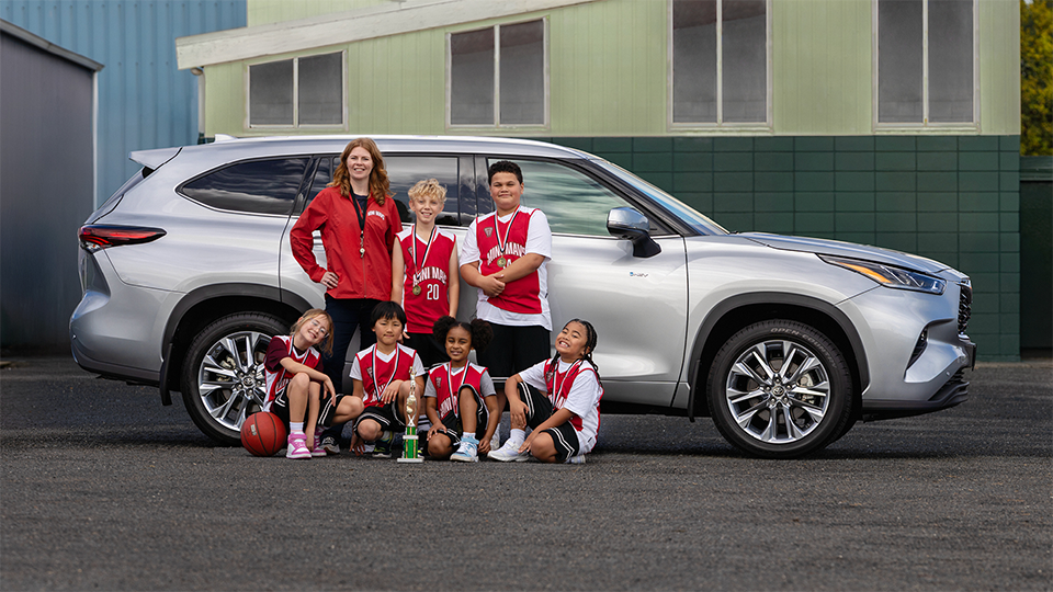A basketball coach with young players standing in front of a car