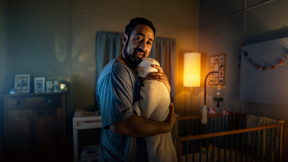 A man holding a baby in a bedroom